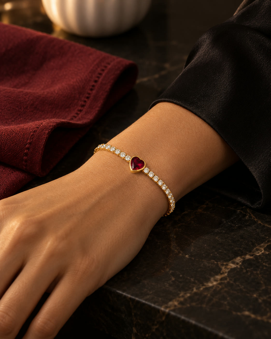 A ruby heart tennis bracelet worn at the wrist in warm light