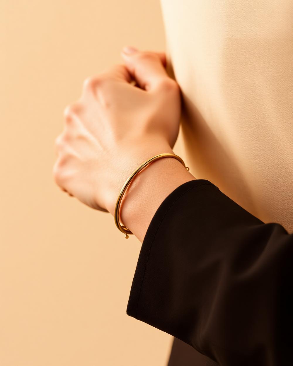 A slim bangle and fine chain bracelet worn at the wrist