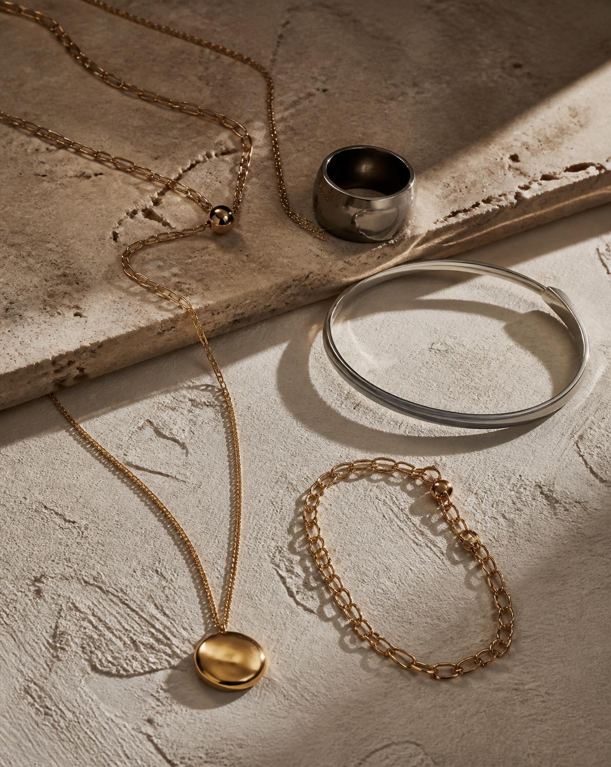 Assorted VYZA jewellery arranged on a warm stone surface